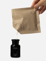 Terra Tonics Elemental Cleanser Refill – Natürlicher Reinigungspuder wird aus der Nachfüllpackung in die schwarze Glasflasche umgefüllt.